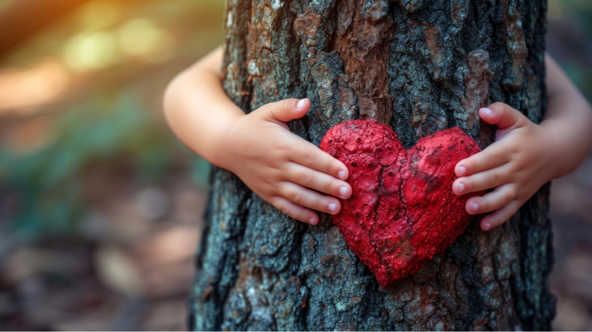 hands of a child surrounding a tree with heart